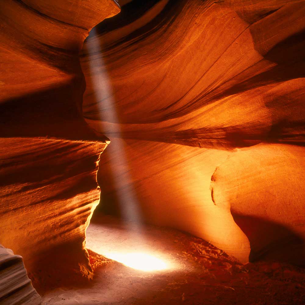 Photographie en clair-obscur d'un rayon de lumière qui illumine le fond de Antelope Canyon