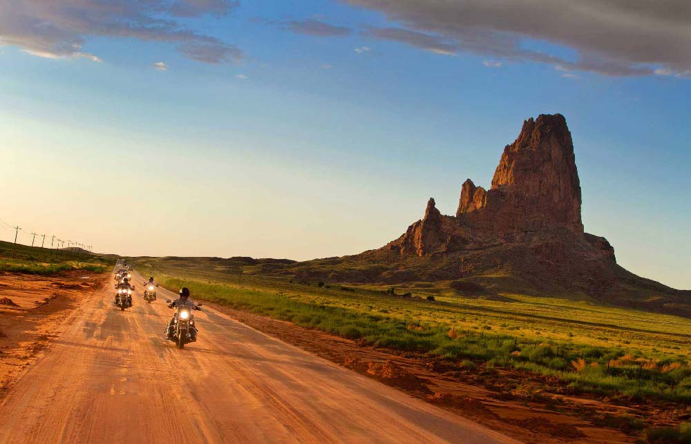Motards sur leur Harley-Davidson roulant dans le soleil couchant de Monument Valley